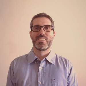 Foto do instrutos Bruno figuinha que é um homem branco com barba que usa óculos